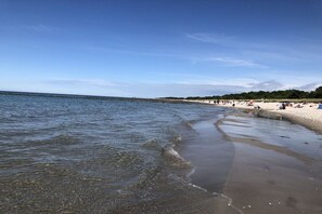A beach with clear water, a pier in the distance, and people on the sand. - 5 in the Damaris house (Zingst)