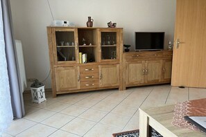 A living room with a wooden cabinet, a television, and a small table. - 5 in the Damaris house (Zingst)