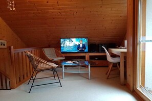 Una habitación acogedora de madera con una televisión, una mesita y dos sillas.