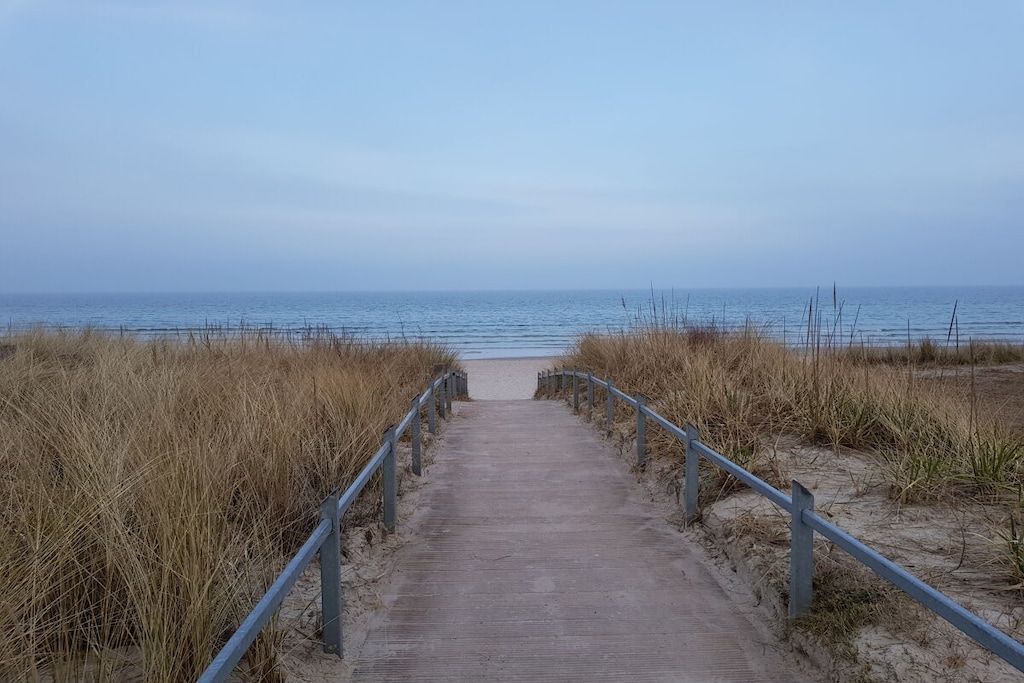 A pathway leading to the beach with metal railings on both sides.