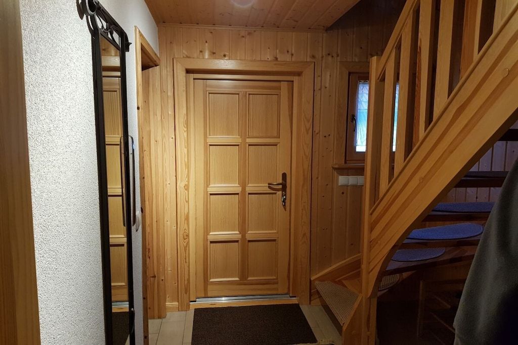 A wooden door with a handle, a wooden staircase, and a small window.