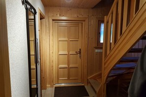 Eine Holztür mit Griff, eine Holztreppe und ein kleines Fenster.