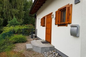 Ein Gebäude mit weißer Fassade, Holzklappen und einem Briefkasten.
