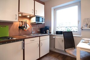 A compact kitchen with a microwave, coffee maker, and utensils on the counter. - Holiday apartment with 0 bedrooms (Rostock)