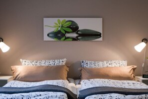 A bedroom with two beds, each with patterned pillows and a wall-mounted artwork above. - Holiday apartment with 0 bedrooms (Rostock)