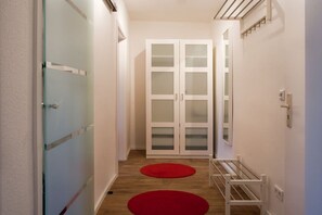A hallway with a glass door, a white wardrobe, and a red rug. - Holiday apartment with 0 bedrooms (Rostock)