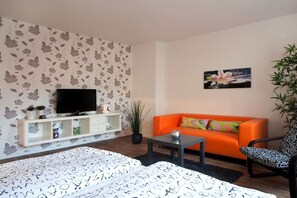 A living room with a sofa, a television, a coffee table, and a patterned rug. - Holiday apartment with 0 bedrooms (Rostock)