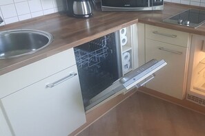 Una cocina con lavavajillas, microondas y pileta.