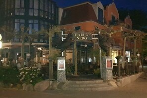 Ein Hotel Eingang mit einem Schild, auf dem 'Gallo Nero' steht, umgeben von Steinsäulen und einem gepflegten Garten.