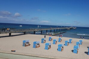 Ein Strand mit Reihen blauer Liegen und einem Steg, der sich ins Wasser erstreckt.