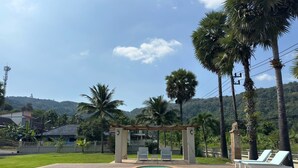 A swimming pool with lounge chairs and a pergola, surrounded by palm trees and a hilly landscape. - Giant Palm Tree Views Retreat. Castle-Style Private Pool Villa. (Chalong)