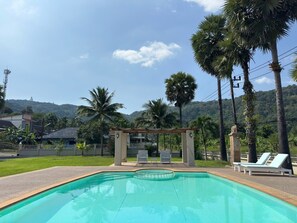 A swimming pool with lounge chairs and a pergola, surrounded by palm trees and a hilly landscape. - Giant Palm Tree Views Retreat. Castle-Style Private Pool Villa. (Chalong)