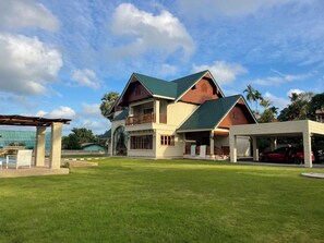 A two-story house with a green roof, a balcony, and a covered patio area. - Giant Palm Tree Views Retreat. Castle-Style Private Pool Villa. (Chalong)