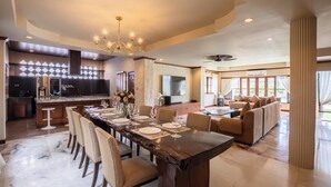 A spacious dining area with a long table, chairs, and a chandelier. - Giant Palm Tree Views Retreat. Castle-Style Private Pool Villa. (Chalong)