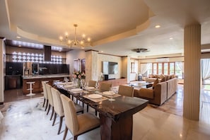 A spacious dining area with a long table, chairs, and a chandelier. - Giant Palm Tree Views Retreat. Castle-Style Private Pool Villa. (Chalong)