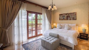 A spacious bedroom with a large bed, a wooden door leading to an outdoor area, and a painting on the wall. - Giant Palm Tree Views Retreat. Castle-Style Private Pool Villa. (Chalong)