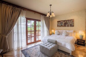 A spacious bedroom with a large bed, a wooden door leading to an outdoor area, and a painting on the wall. - Giant Palm Tree Views Retreat. Castle-Style Private Pool Villa. (Chalong)