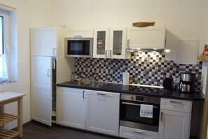 A compact kitchen with white cabinets, a microwave, a sink, and a coffee maker. - Holiday apartment with 1 bedroom (Ribnitz-Damgarten)