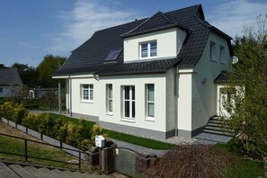 Ein zweistöckiges Haus mit Satteldach, einer Veranda und einem kleinen Garten.