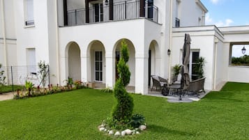 Un bâtiment à deux étages doté d’un patio couvert, d’un espace extérieur aménagé pour s’asseoir et d’une pelouse bien entretenue.