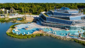 Un hôtel moderne doté d’un grand espace piscine, comprenant un jacuzzi et un toboggan aquatique.