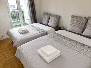 Habitación de hotel con dos camas, cada una con una almohada y una toalla doblada.