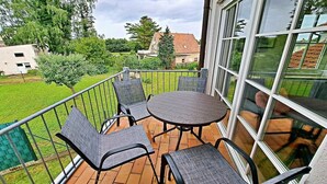 Un balcone con un tavolo tondo e quattro sedie, delimitato da una ringhiera metallica.