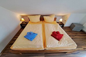 A double bed with two pillows, a blue towel, and a red towel. - Tinnemeyer holiday apartment (Heringsdorf (Seebad))