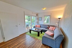 A living room with a sofa, coffee table, and a view of the outdoors. - Tinnemeyer holiday apartment (Heringsdorf (Seebad))
