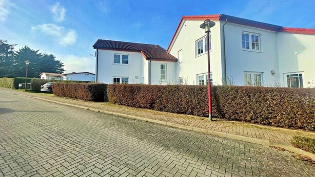 Un edificio residenziale con vialetto lastricato e siepe.