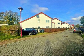 A residential street with houses, a parked car, and a street lamp. - Tinnemeyer holiday apartment (Heringsdorf (Seebad))