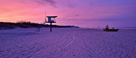 A lifeguard tower on a beach with a boat in the distance.