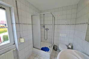 Uma casa de banho com chuveiro, sanita e banheira.