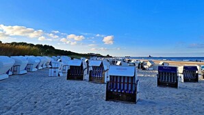 Casette sulla spiaggia disposte in file su una spiaggia sabbiosa, con cielo sereno.