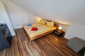 A single bed with a wooden frame, two bedside lamps, and a bedside table with a lamp. - Tinnemeyer holiday apartment (Heringsdorf (Seebad))