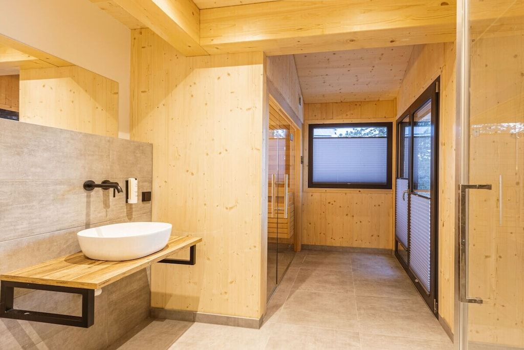 Ein Holzinnenraum mit einem modernen Badezimmer, inklusive Waschbecken und Fenster.