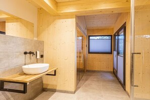 Interior de madera con un baño moderno, que incluye un lavamanos y una ventana.