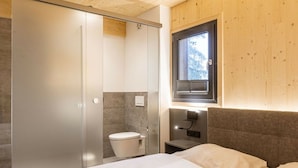 A modern bedroom with a bed, a window, and a separate toilet area. - Superior Chalet # 2 with Sauna & Hot Tub (Turrach)