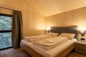 Un dormitorio con paneles de madera, una cama, lámparas de noche y una ventana con cortinas.