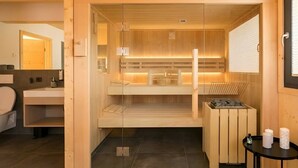 Uma sala de sauna com paredes de madeira, porta de vidro, um banco e um aquecedor.
