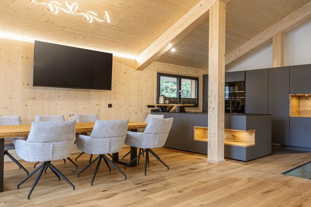 Ein modernes Interieur mit Essbereich, Küche und einem großen Flachbildfernseher an der Wand.