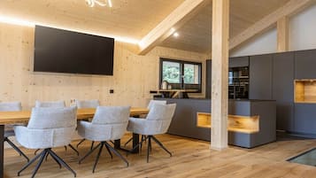 Ein modernes Interieur mit Essbereich, Küche und einem großen Flachbildfernseher an der Wand.