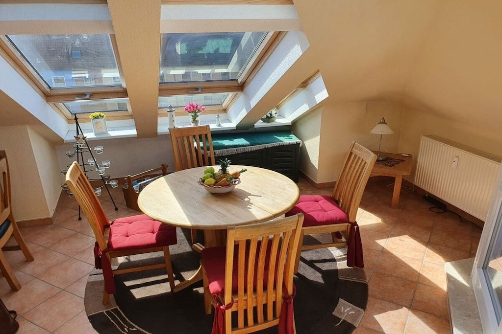 Ein Essbereich mit einem runden Tisch, Stühlen und Blick ins Freie durch Dachfenster.
