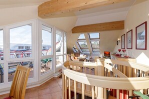 A room with a wooden ceiling, large windows, a dining area with a table and chairs, and a view of the outside. - Dune Garden Kühlungsborn (Kühlungsborn)