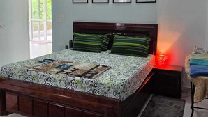 Quarto com cama, mesa de cabeceira, abajur e quatro quadros na parede.