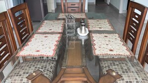 A dining area with a glass-top table, wooden chairs, and a central decorative item.