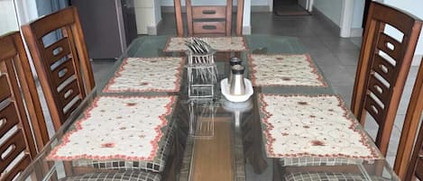 Un comedor con una mesa de vidrio, sillas de madera y un elemento decorativo central.