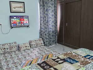 A room with a sofa, a television mounted on the wall, and a wardrobe.