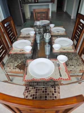 A dining table set with plates, glasses, and cutlery, surrounded by wooden chairs. - The Riverside Retreat is a comfortable riverfront home in the Doon Valley. India (Dehradun)