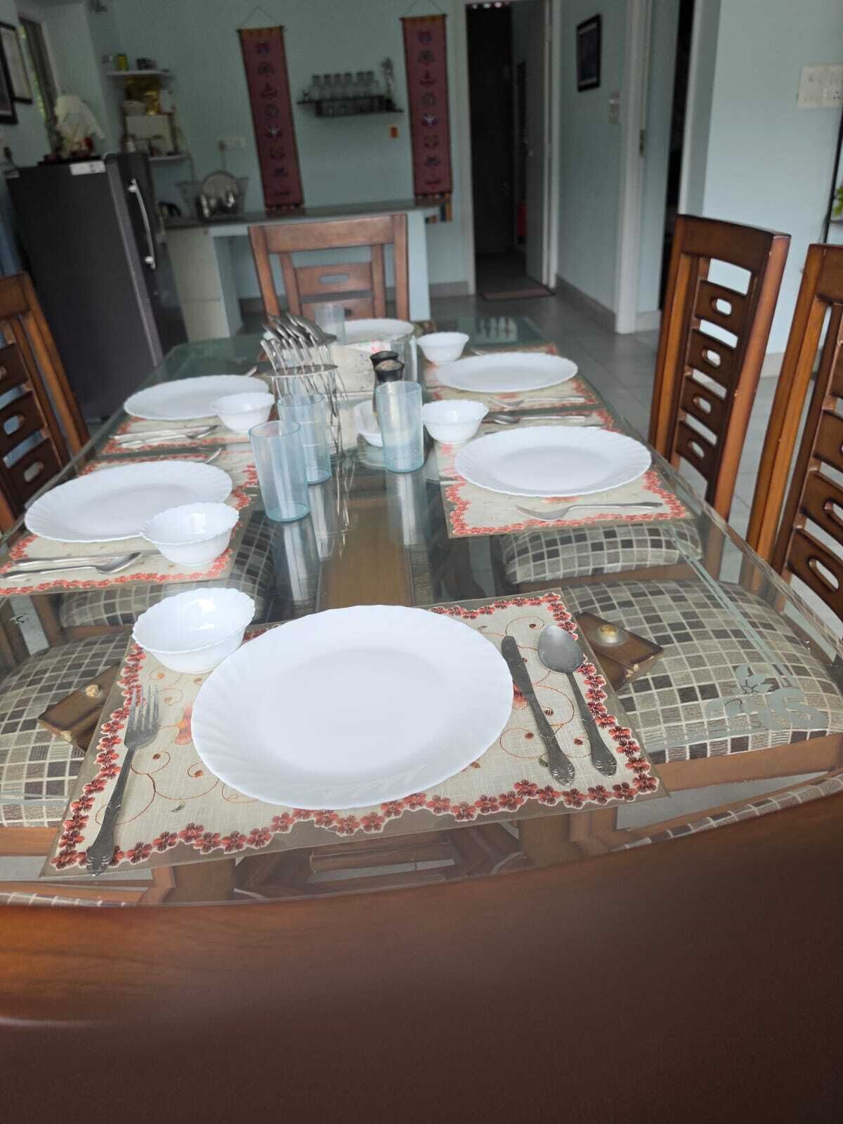 A dining table set for six with plates, cutlery, and glasses.